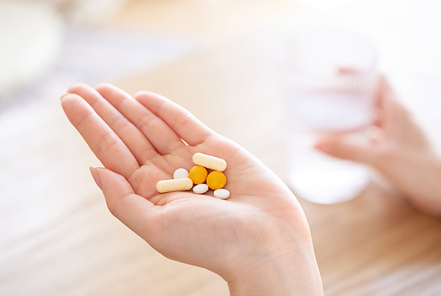 手のひらに錠剤を乗せ反対の手にはコップ